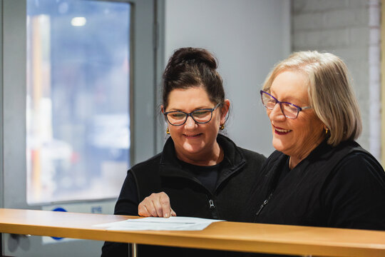 Two female office workers having conversation about paperwork