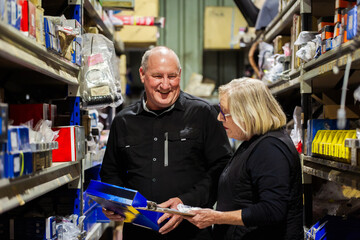 Parts person in mechanics workshop talking with woman customer about spare vehicle supplies
