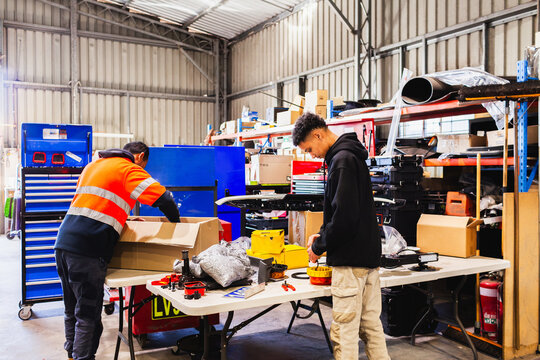 Two male mechanics working on beacon lights for light bar inside workshop