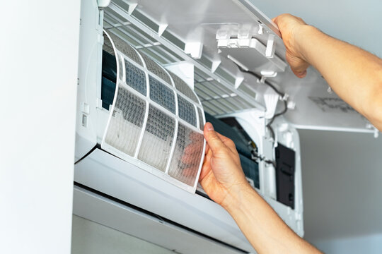 Repairmans hands changes cleaning filter in air conditioner. Air conditioning maintenance. Purification and repair of cooling system