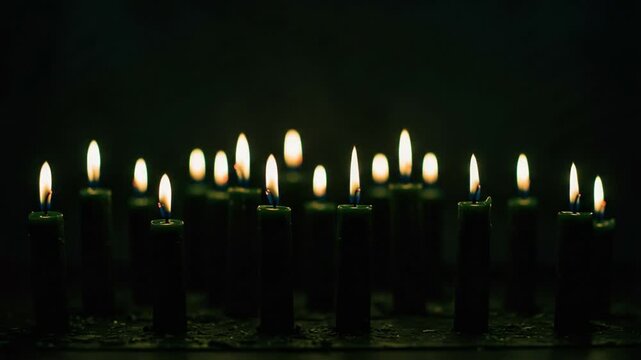 A Mesmerizing Display of Flickering Candlelight: A Serene Atmosphere Created by Multiple Illuminated Candles in a Darkened Setting