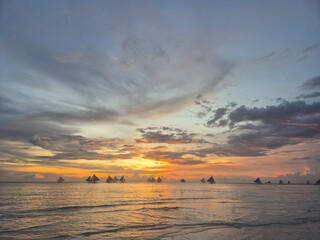 Spectacular sunset seascape at Boracay White Beach Philippines with traditional paraw sailboats...