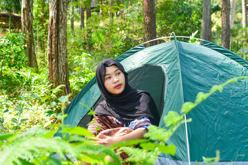An Indonesian woman wearing traditional Indonesian clothing is lying on a checkered blanket with a...
