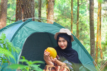 An Indonesian woman wearing traditional Indonesian clothing is lying on a checkered blanket with a...