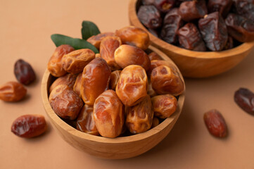 Delicious dried dates of different varieties in wooden bowls on brown background top view. Oriental fruit, date palm fruit, natural sweet dessert. Organic healthy snack, food background