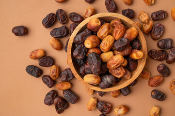 Delicious dried dates of different varieties in wooden bowls on brown background top view. Oriental fruit, date palm fruit, natural sweet dessert. Organic healthy snack, food background