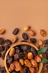 Delicious dried dates of different varieties in wooden bowls on brown background top view. Oriental fruit, date palm fruit, natural sweet dessert. Organic healthy snack, food background