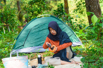 An Indonesian woman wearing traditional Indonesian clothing is lying on a checkered blanket with a...