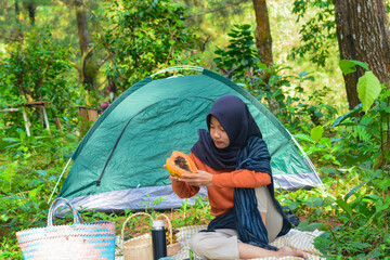An Indonesian woman wearing traditional Indonesian clothing is lying on a checkered blanket with a...