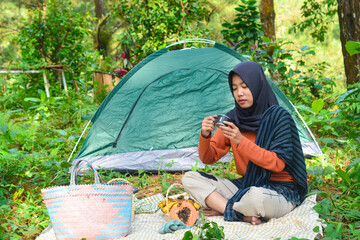 An Indonesian woman wearing traditional Indonesian clothing is lying on a checkered blanket with a...