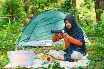 An Indonesian woman wearing traditional Indonesian clothing is lying on a checkered blanket with a...
