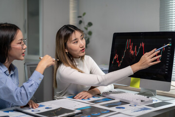 Businesswomen analyzing financial charts on computer screen in office meeting