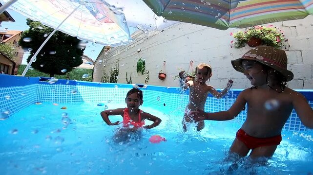 Happy children splashing in a backyard swimming pool