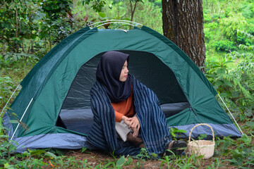 An Indonesian woman wearing traditional Indonesian clothing is lying on a checkered blanket with a...
