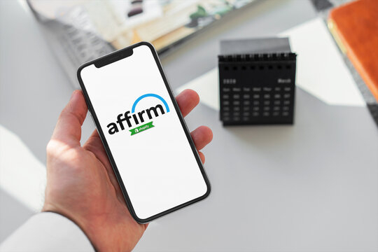 Businessman holding smartphone with affirm app on screen in office