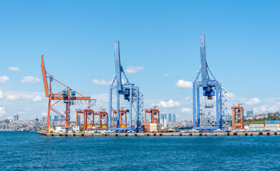Fototapeta premium Industrial harbor with colorful cranes and skyline view in city during clear day
