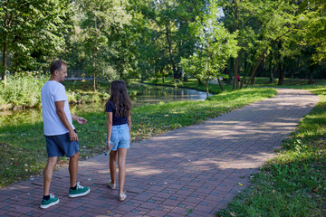Obraz premium Father and daughter in the park on a summer morning spending time together enjoying nature.