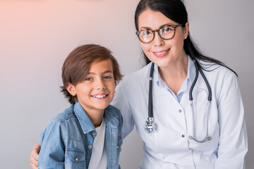 Portrait of school boy and doctor have consultation in hospital room. Looking at camera. Female...
