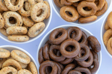 Freshly baked mini bagels on a dark background. Top view. Pretzels in the form of a ring close-up. Small bread circle biscuit. Bowls with different types of bagels.
