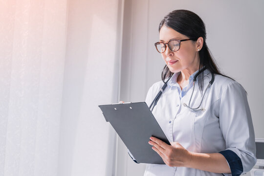Doctor with stethoscope writing prescription on clipboard. Female medical worker nurse taking notes, noting diagnosis, test results, medical prescription, side effect of drugs history