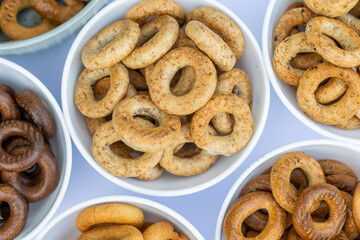 Freshly baked mini bagels on a dark background. Top view. Pretzels in the form of a ring close-up. Small bread circle biscuit. Bowls with different types of bagels.