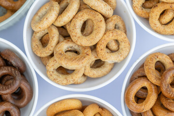 Freshly baked mini bagels on a dark background. Top view. Pretzels in the form of a ring close-up. Small bread circle biscuit. Bowls with different types of bagels.