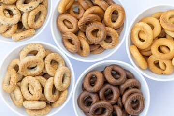 Freshly baked mini bagels on a dark background. Top view. Pretzels in the form of a ring close-up. Small bread circle biscuit. Bowls with different types of bagels.