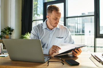Fototapeta premium Focused young businessman reviewing documents in a bright modern office space