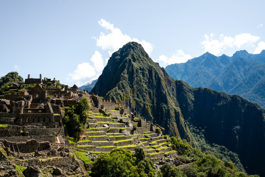 Panoramablick auf die historischen Steinruinen und Terrassenfelder von Machu Picchu, Peru, mit dem markanten Huayna Picchu Berg - Powered by Adobe