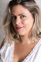 Selective focus portrait of beautiful smiling blond young woman wearing a white cotton frilly top