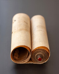 Ancient vintage paper scroll roll with a rolling wooden stick on black background with shallow depth of field.