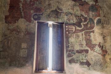 View on historic Buddhist half-erased frescoes on stone wall and wooden shutters on window at Thai Buddhist temple in Phra Nakhon Si Ayutthaya Province