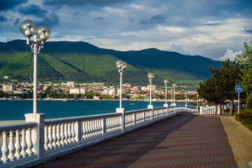Obraz premium Gelendzhik city. Spa promenade with balustrade and lanterns. Pitsunda pine. In background Gelendzhik Bay and Caucasus Mountains.