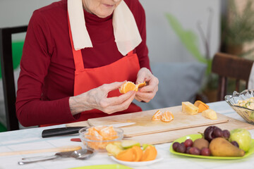 Elderly woman preparing fruit salad at home in the living room