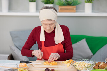 Elderly woman preparing fruit salad at home in the living room