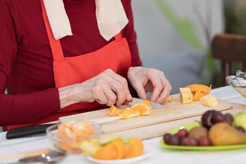 Elderly woman preparing fruit salad at home in the living room