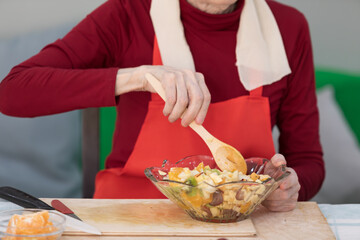 Elderly woman preparing fruit salad at home in the living room