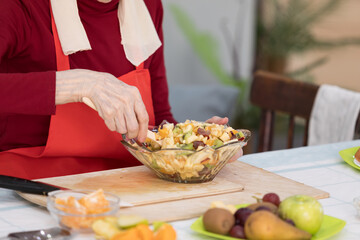 Elderly woman preparing fruit salad at home in the living room