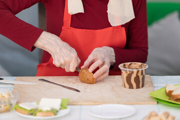 Elderly woman preparing a butter sandwich