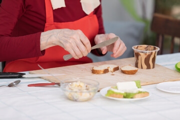 Elderly woman preparing a butter sandwich
