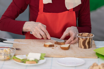 Elderly woman preparing a butter sandwich