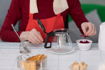 Elderly woman preparing a tea at home in the living room