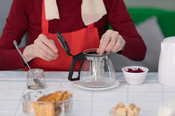 Elderly woman preparing a tea at home in the living room