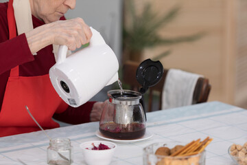 Elderly woman preparing a tea at home in the living room