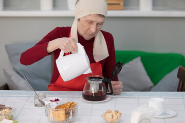 Elderly woman preparing a tea at home in the living room