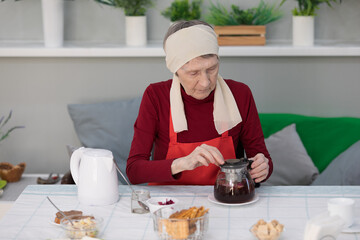 Elderly woman preparing a tea at home in the living room