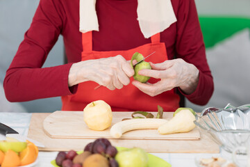 Elderly woman preparing fruit salad at home in the living room