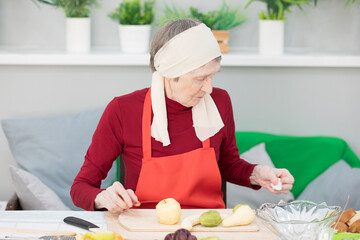 Elderly woman preparing fruit salad at home in the living room