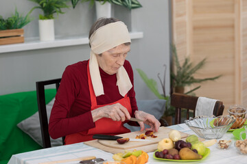 Elderly woman preparing fruit salad at home in the living room