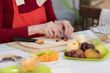 Elderly woman preparing fruit salad at home in the living room